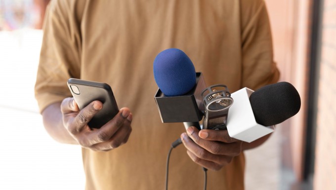 Un homme tenant deux microphones et un enregistreur numérique.