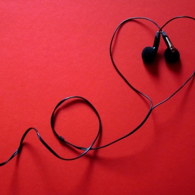 Casque audio sur fonds rouge. Le câble du casque forme un coeur