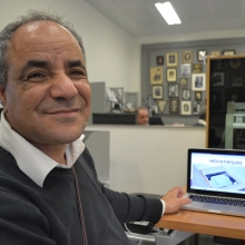 Portrait d'Abder ragui devant un ordinateur portable affichant l'accueil d'une portail des médiathèques de Rennes métropole