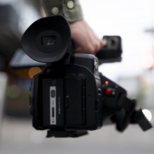 Photo d'une caméra en gros plan tenue par un journaliste.