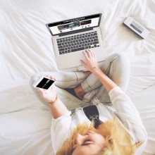 Photo d'une femme consultant simultanément un ordinateur portable et un smartphone.