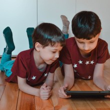 Deux enfants allongés par terre avec une tablette